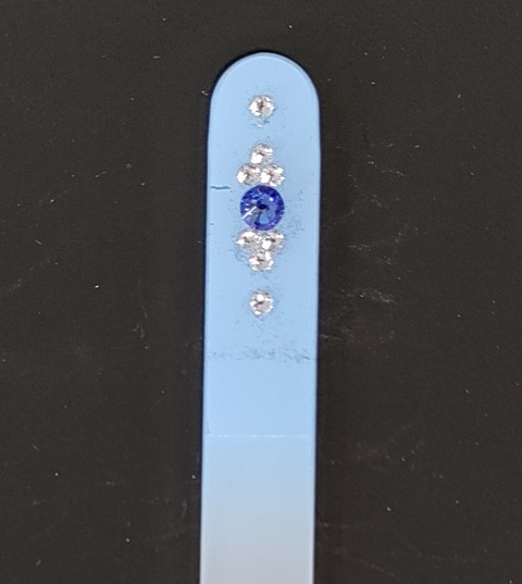Nagelvijl met blauwe/transparante Swarovski steentjes op een lichtblauwe achtergrond