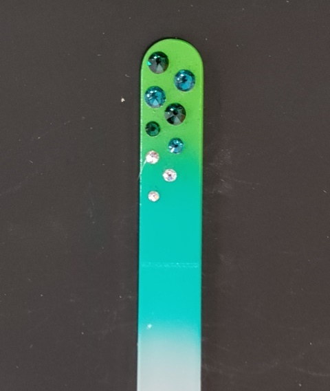 Nagelvijl met groene Swarovski steentjes op een licht-/donker-groene achtergrond