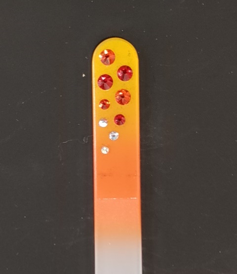 Nagelvijl met rode Swarovski steentjes op een geel/oranje achtergrond